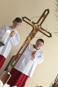 Wizerunek krzyża świętego oraz ministrantów.