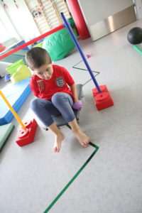 Chłopiec podczas ćwiczenia koordynacji z wykorzystaniem deskorolki.