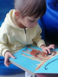 Dziewczynka podczas aktywności terapeutycznej wykorzystaniem tematycznej książeczki o piesku.