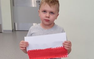 chłopeic trzymający wykonaną przez siebie flagę Polski.
