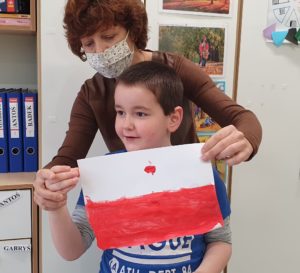 Chłopiec wraz z nauczycielem trzymający flagę Polski.