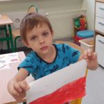 Chłopiec trzymający wykonaną przez siebie flagę Polski.