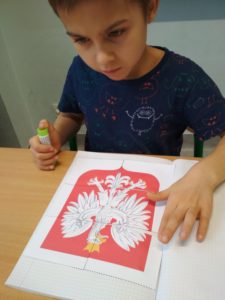 Chłopiec wyklejający godło Polski z gotowych elementów.