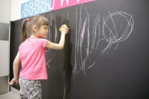Dziewczynka zmazująca krędę z tablicy za pomocą gąbki.
