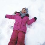 Dziewczynka leżąca na śniegu, rąbiąca "aniołka".