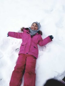 Dziewczynka leżąca na śniegu, rąbiąca "aniołka".