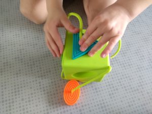 Dłonie manipulujące zabawką dopasowując kształt do otworu.