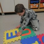 Chłopiec układający puzzle z samogłoskami.