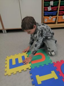 Chłopiec układający puzzle z samogłoskami.
