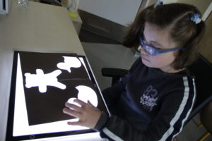Uczennica podczas ćwiczenia rozwijającego percepcję wzrokową z wykorzystaniem podświetlanej tablicy.