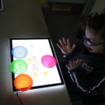 Uczennica podczas ćwiczenia rozwijającego percepcję wzrokową z wykorzystaniem podświetlanej tablicy.