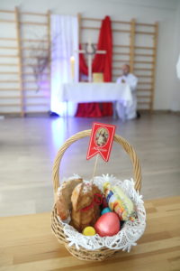 Koszyczek ze święconką na tle dekoracji ołtarza.