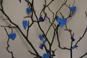 Wizerunak fragmenty drzewwa - gałęzi przyozdobionych niebieskimi, papierowymi sercami.