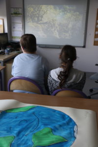 Uczniowie oglądający prezentajcę multimedialną z okazji Dnia Ziemii.