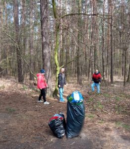 Uczniowie w lesie podczas zajęć z zakresu dbania o czystość śrdowiska.