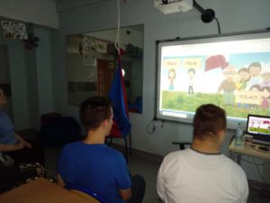 Grupa uczniów obserwująca patriotyczną prezentacje na tablicy multimedialnej.