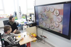 Uczeń wraz z teraputą AAC podczas zadania wyboru odpowiedniego zwierzęcia na tablicy interaktywnej z wykorzystanie specjalistycznej myszki.