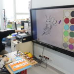 Uczeń wraz z teraputą podczas pracy na tablicy interaktywnej z wykorzystaniem dostosowanej do potrzeb niepełnosprawnych ruchowo osób specjalistycznej "myszki:.