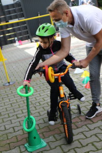Uczennica wukonująca z pomoca zadanie koordynacyjne na czterokołowym rowerze.