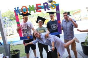 Uczniowie wraz z nauczycielami pozujący w kolorowej ramce z napisem Komers.