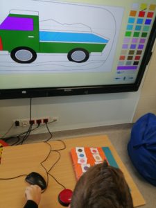 Fragment tablicy interaktwynej z kolorowanką, oraz uczeń dokonujący wyboru koloru z wykorzystaniem symboli kolorów PCS.