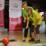 Uczestnicy turnieju w trakcie rzutu kulą bowlingową.