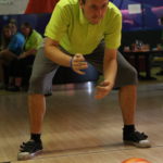 Uczestnik turnieju w trakcie rzutu kulą bowlingową.