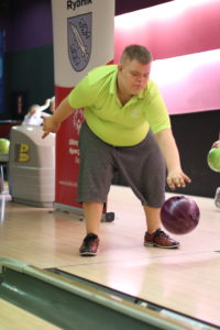 Uczestnik turnieju w trakcie rzutu kulą bowlingową.