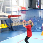 Młody sportowiec podczas aktywności rzutu piłką do kosza.