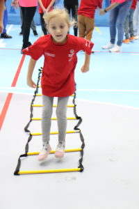 Młody sportowiec podczas aktywności skoku przód ponad płaskimi poprzeczkami.