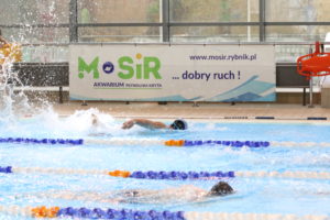 Fragment basenu w trakcie konkurencji st. dowolnym, w tle logo MOSiR Rybnik