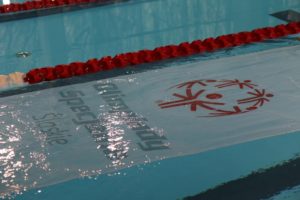 Flaga OSŚ na tafli wody basenu w trakcie Ceremonii Otwarcia zawodów.