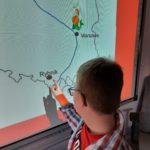 Uczeń wskazujący na tablicy interaktywnej swoje miasto na konturze mapy polski.