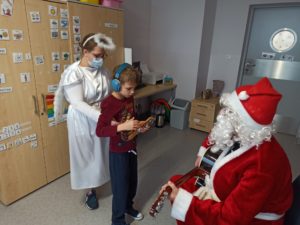 Uczeń w towarzystwie aniołka podczas wręczania prezentu od Mikołaja.