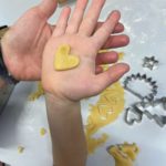 Dłonie prezentujące wykrojone ciasteczko w kształcie serca.