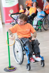 Uczeń na wózku inwalidzkim podczas konkurencji nakładania obręczy na stojak.