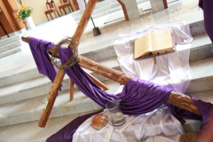 Dekoracja wielkopostna ołtarza (krzyż z filoetowym suknem, chleb, pismo św., wino, korona cierniowa.