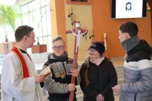 Uczniowie wraz z księdzem prezentujący wykonany przez nich krzyż w trakcie rekolekcyjnej Drogi Krzyżowej.