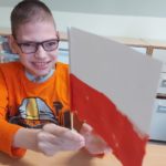 Uczeń preznetyjący wykonaną flagę polski.