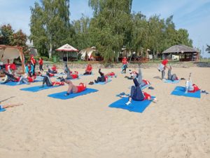 Uczestnicy pikniku ćwiczący na matach na plaży.