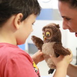 Nauczycielka prezentująca chłopcu pacynkę sowę.