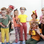 Zdjęcie grupowe dzieci oraz nauczycielki w nakryciach głowy z wizerunkami zwierzątek .