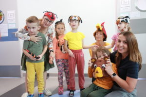 Zdjęcie grupowe dzieci oraz nauczycielki w nakryciach głowy z wizerunkami zwierzątek .
