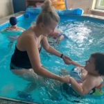 Przedszkolaki wraz z wychowawcą podczas aktywności w basenie.