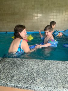 Przedszkolaki oraz wychowawca podczas aktywności w basenie.