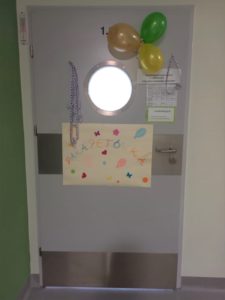 Udekorowane drzwi sali przedszkolne (balony, plakat z napisem "parapetówka").