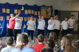 Taneczny występ grupy uczniów na sali gimnastycznej.