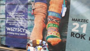 Plakat Dnia Zespołu Downa prezentujący zdajcie różnych kolorowych skarpet nie do pary.