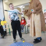 Przedszkolakw towarzystwie nauczycielki przebranej za kurę podczas zabawy w łowienie na wędke.