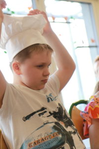 Przedszkolak pozujący w czapce kucharskiej.